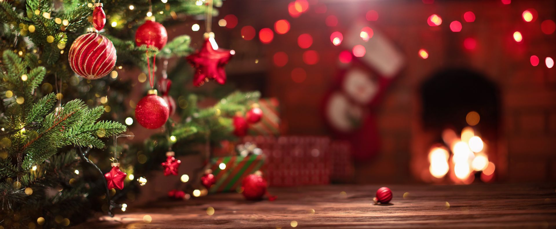 Christmas tree with red ornaments in a cozy room with a fireplace and stockings.