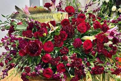Flower arrangements line an aisle in a softly lit wedding venue with candles and brick pillars.