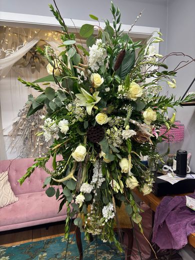 White rose bridal bouquet with eucalyptus, tied with cream ribbon against a white dress