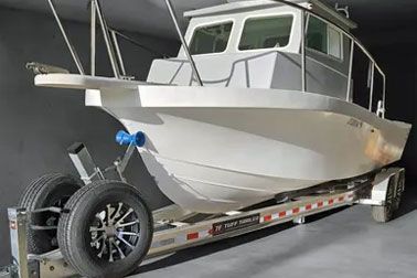 White boat on a trailer, in a dark indoor space.