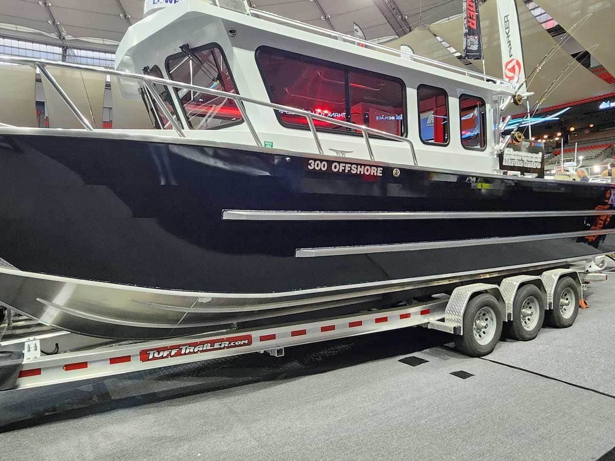 Dark blue and white boat on a trailer, displayed at a boat show.