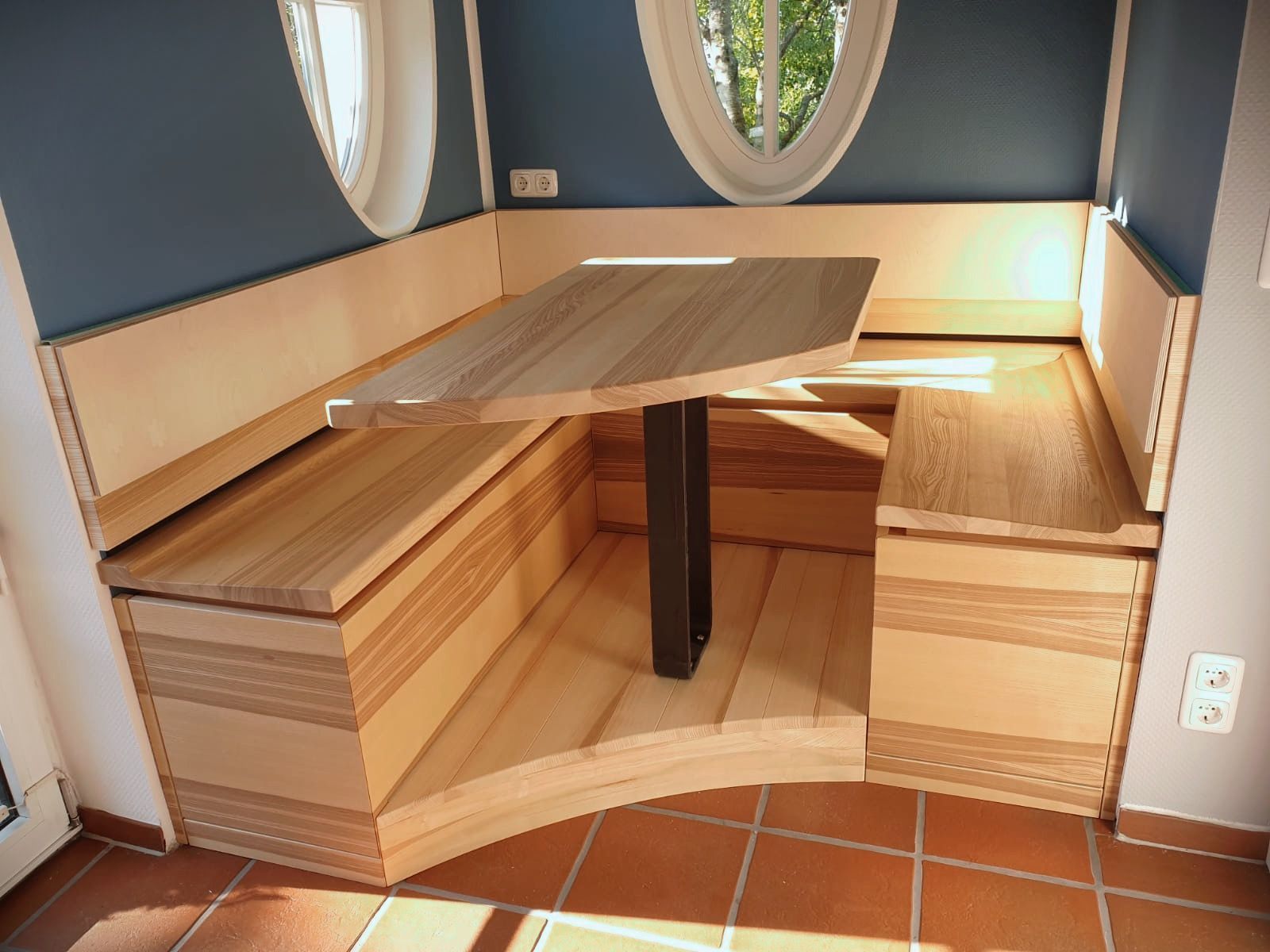 Eingebaute Sitznischen aus Holz mit einem zentralen Tisch in einem kleinen gefliesten Raum