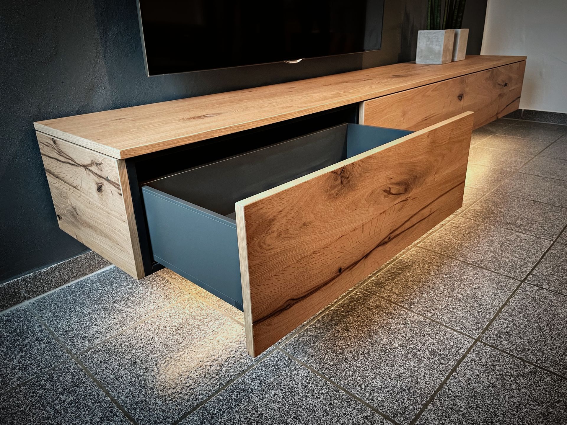 Holzschrank mit Glastüren, hinter dem Reihen von Schüsseln, Tassen und Tellern auf Regalen ausgestellt sind.