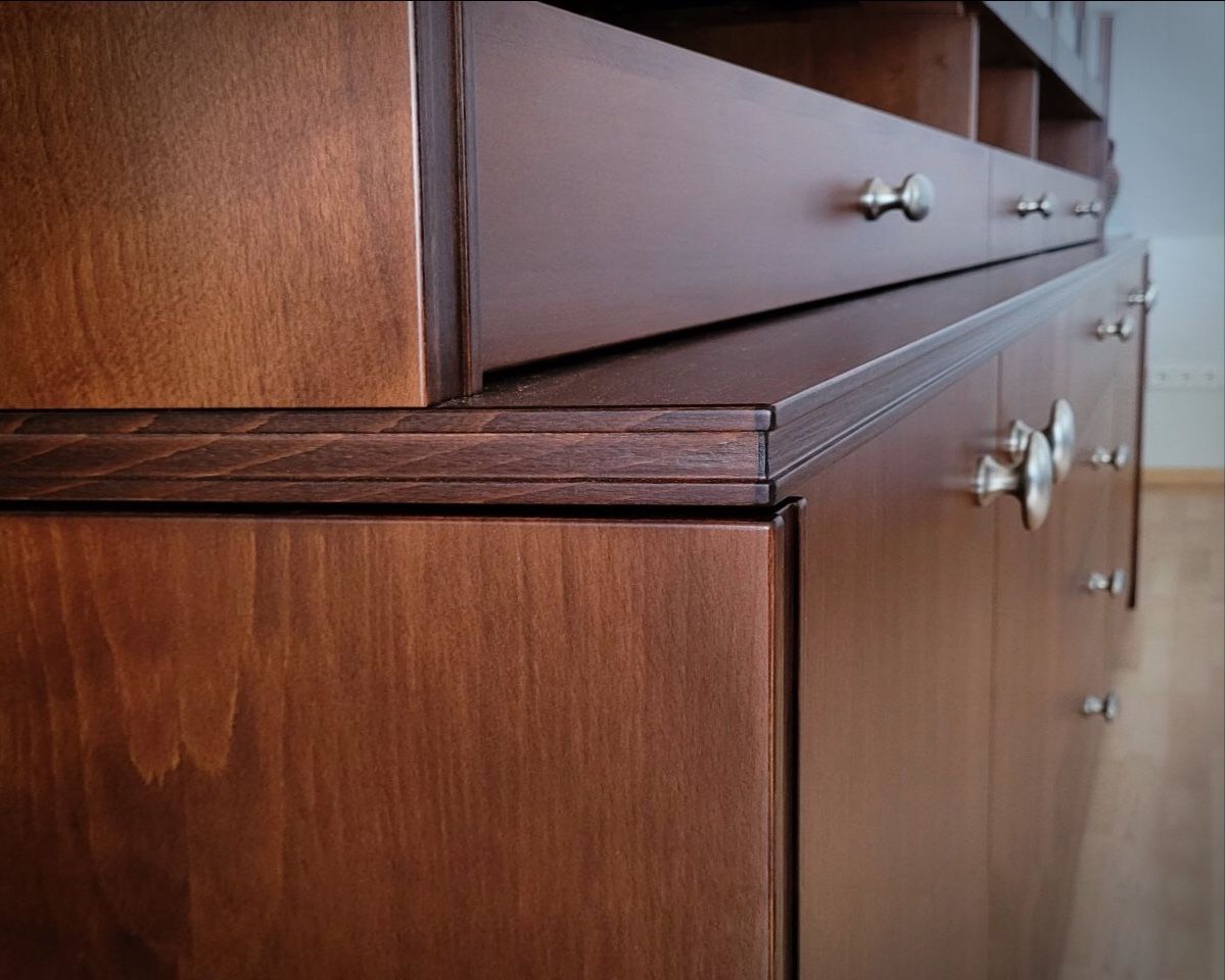 Nahaufnahme einer Holzkommode mit Schubladen und silbernen Knöpfen, schräg aufgenommen.