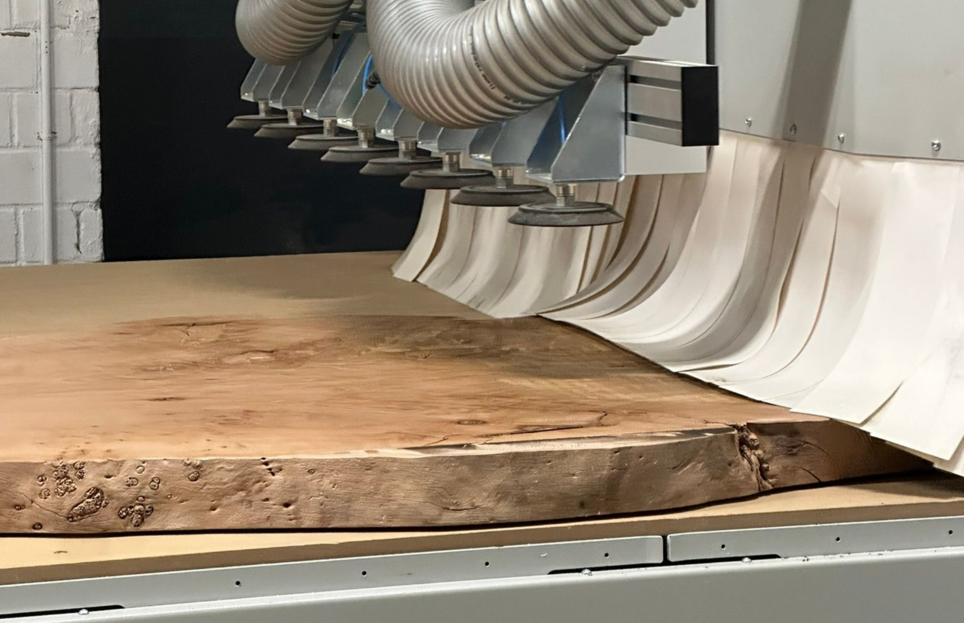 Eine große Holzplatte wird von einer CNC-Maschine mit Staubabsaugung zugeschnitten.