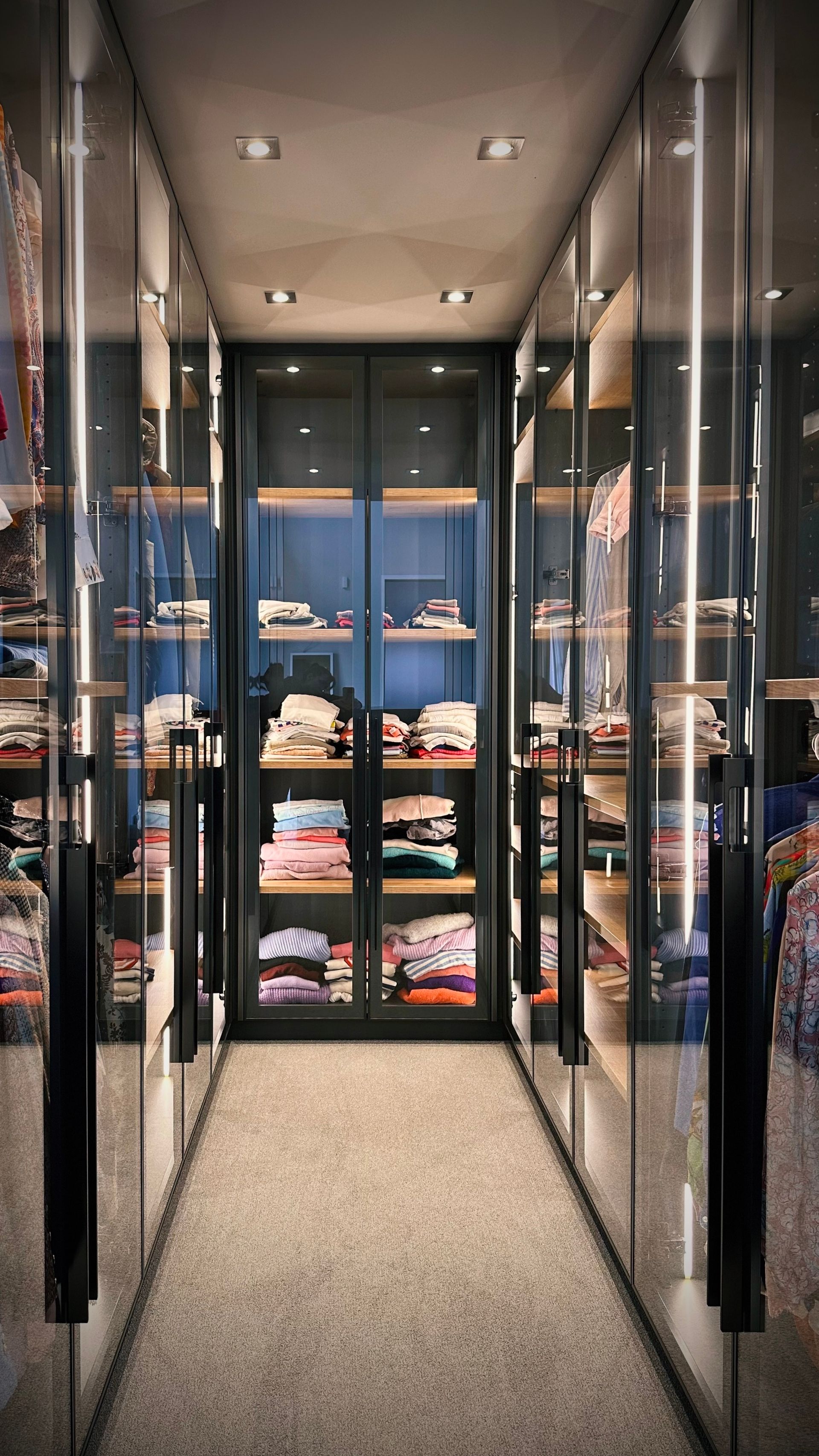 Schmaler Boutique-Flur mit verspiegelten Wänden und Regalen mit gefalteter Kleidung am Ende