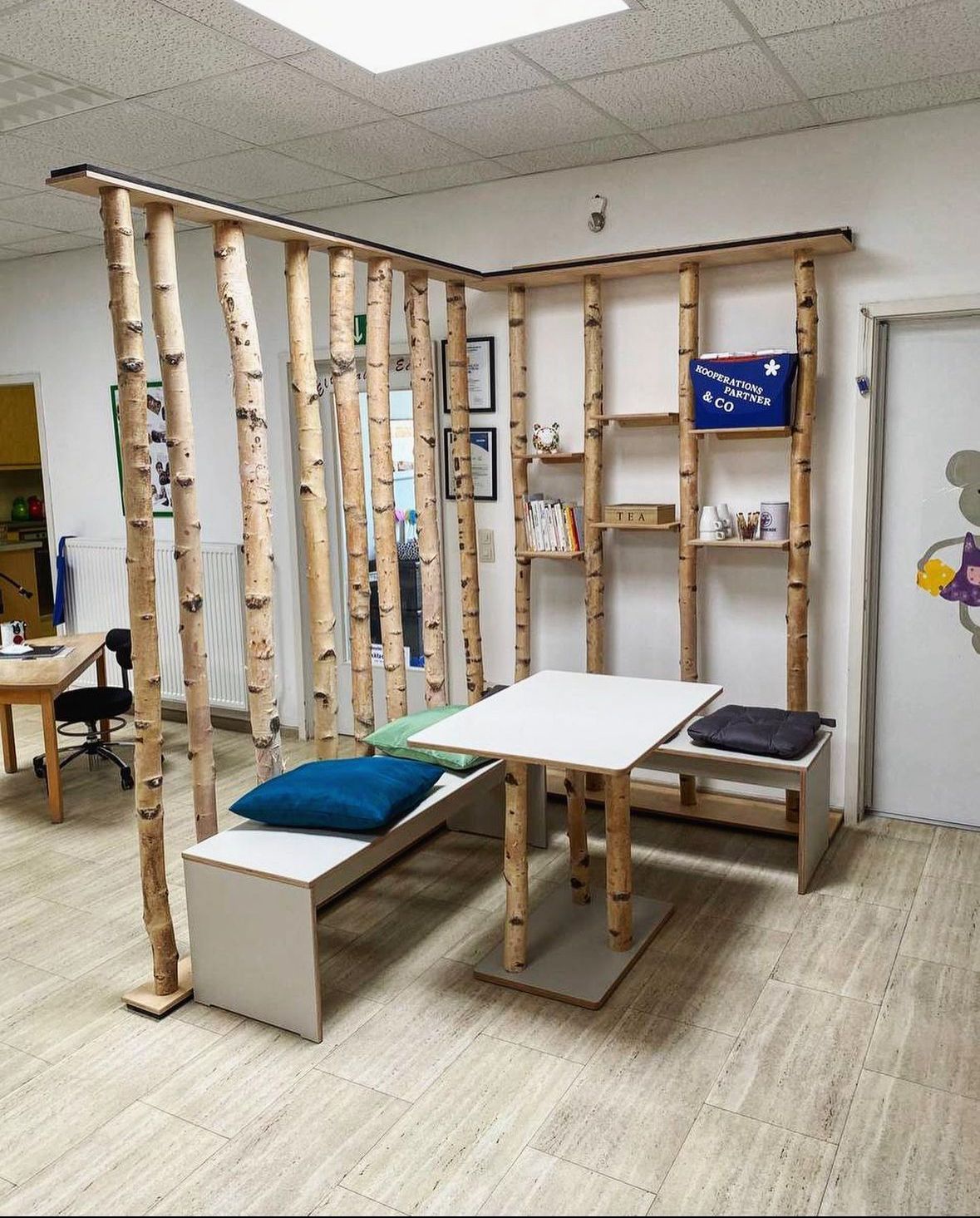 Therapieraum im Innenbereich mit hölzernem Klettergerüst, niedrigen Tischen, Kissen und Regalen