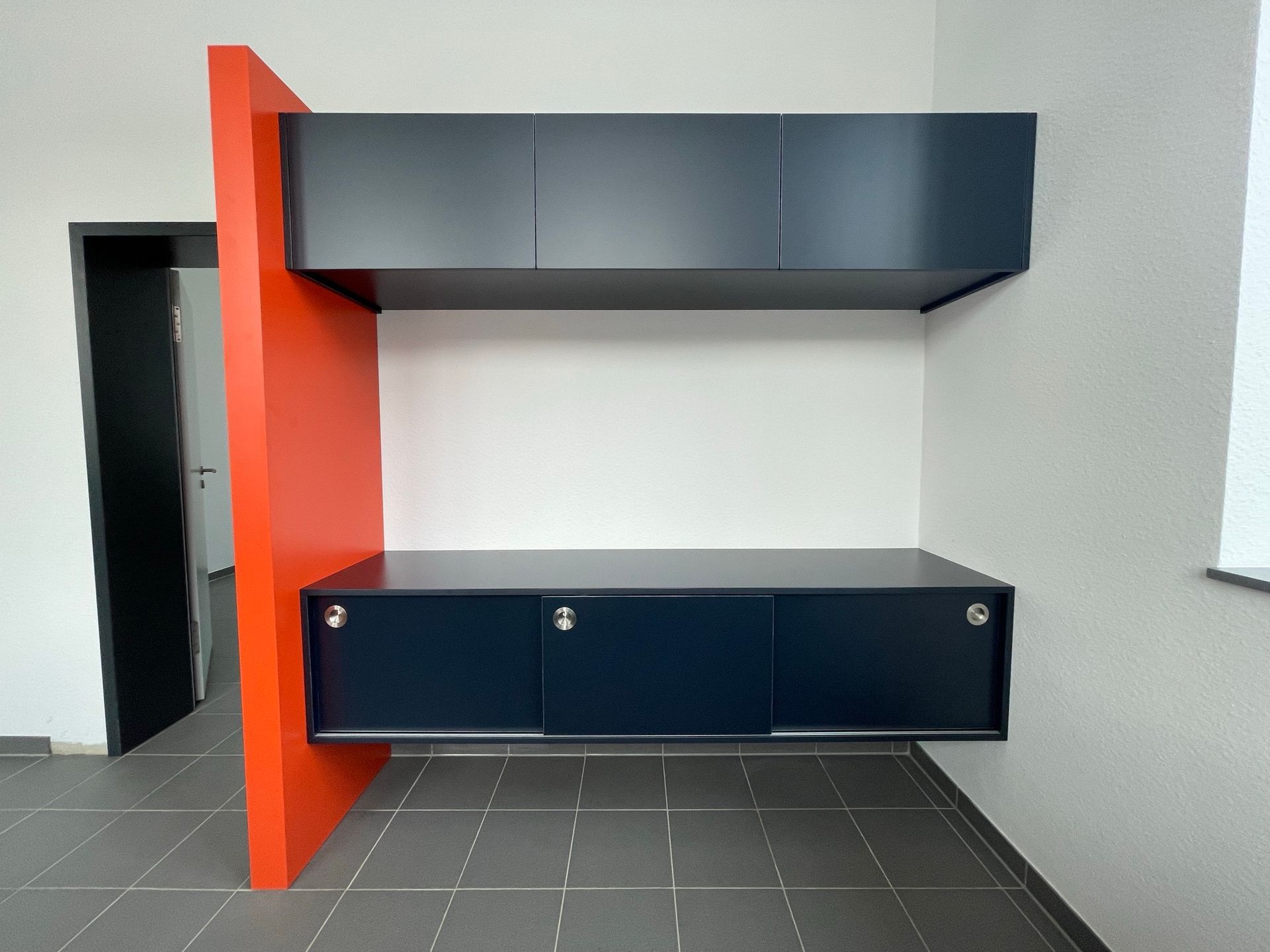 Moderner Einbauschrank mit dunkelblauem Stauraum, orangefarbener Trennwand und grauer Wand in einem Zimmer