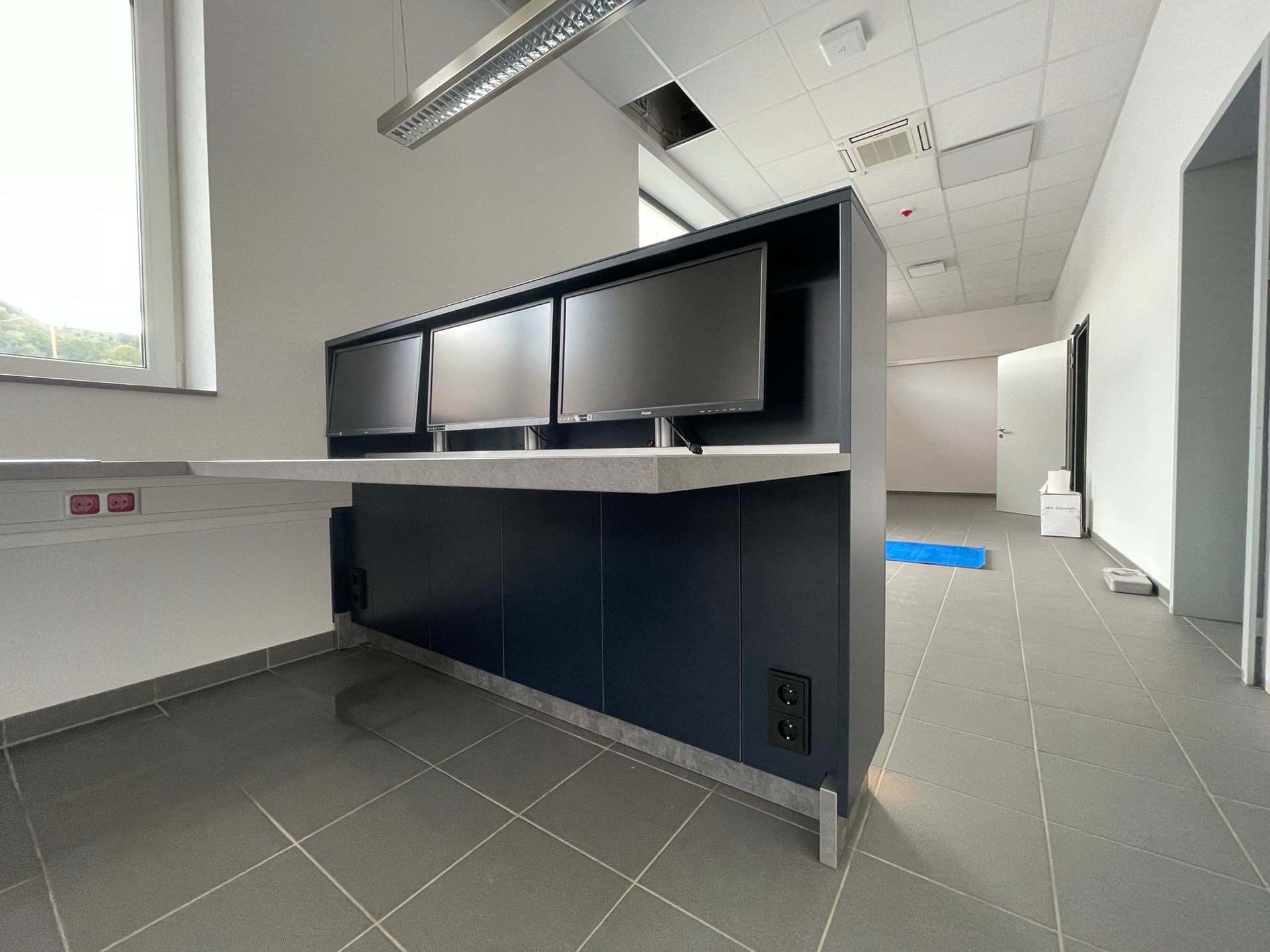 Leeres, modernes Büro mit dunklem Empfangstresen und Fliesenboden unter Neonlicht