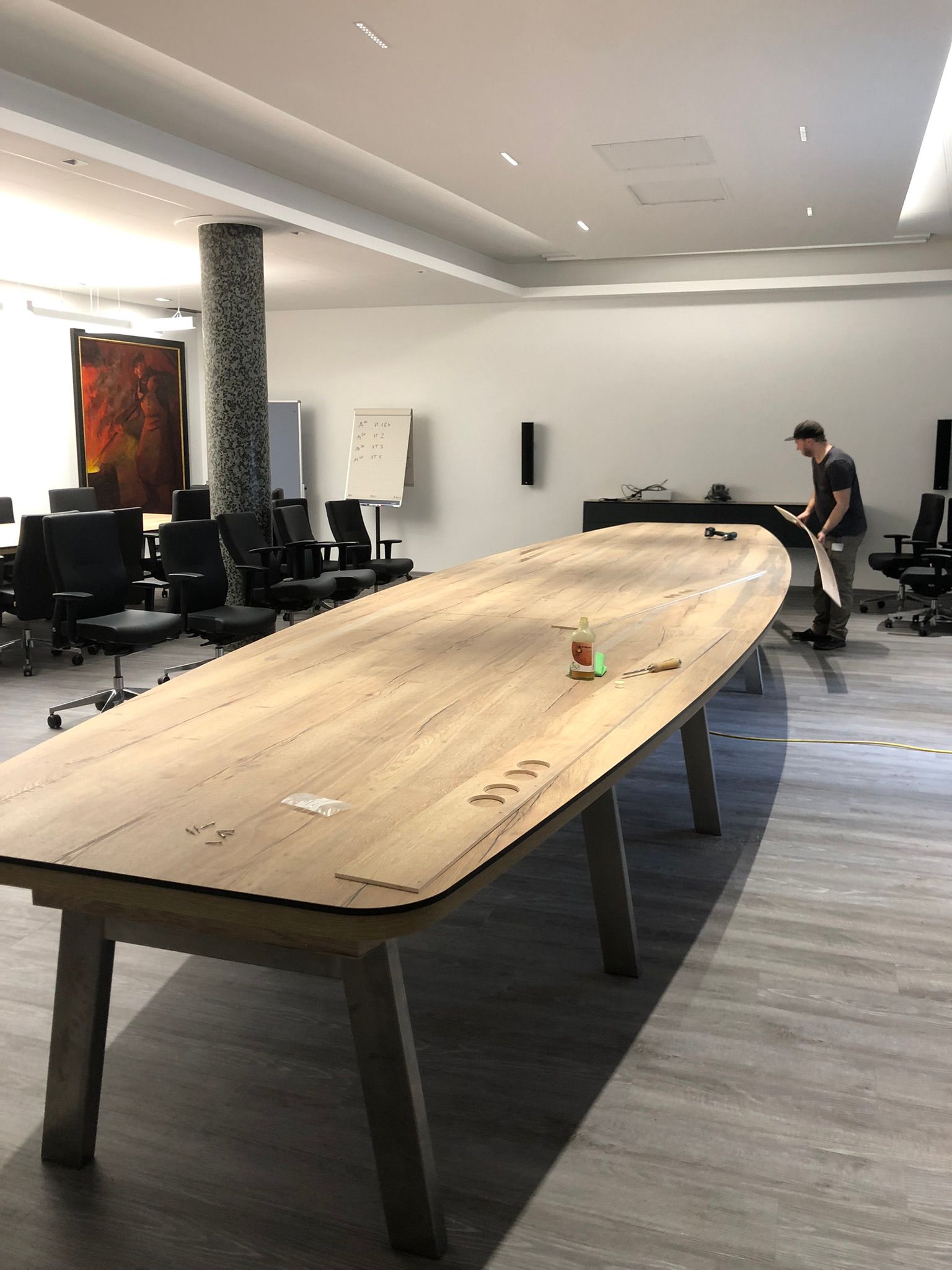 Konferenzraum mit einer langen Tischtennisplatte aus Holz und einer Person, die am anderen Ende steht.