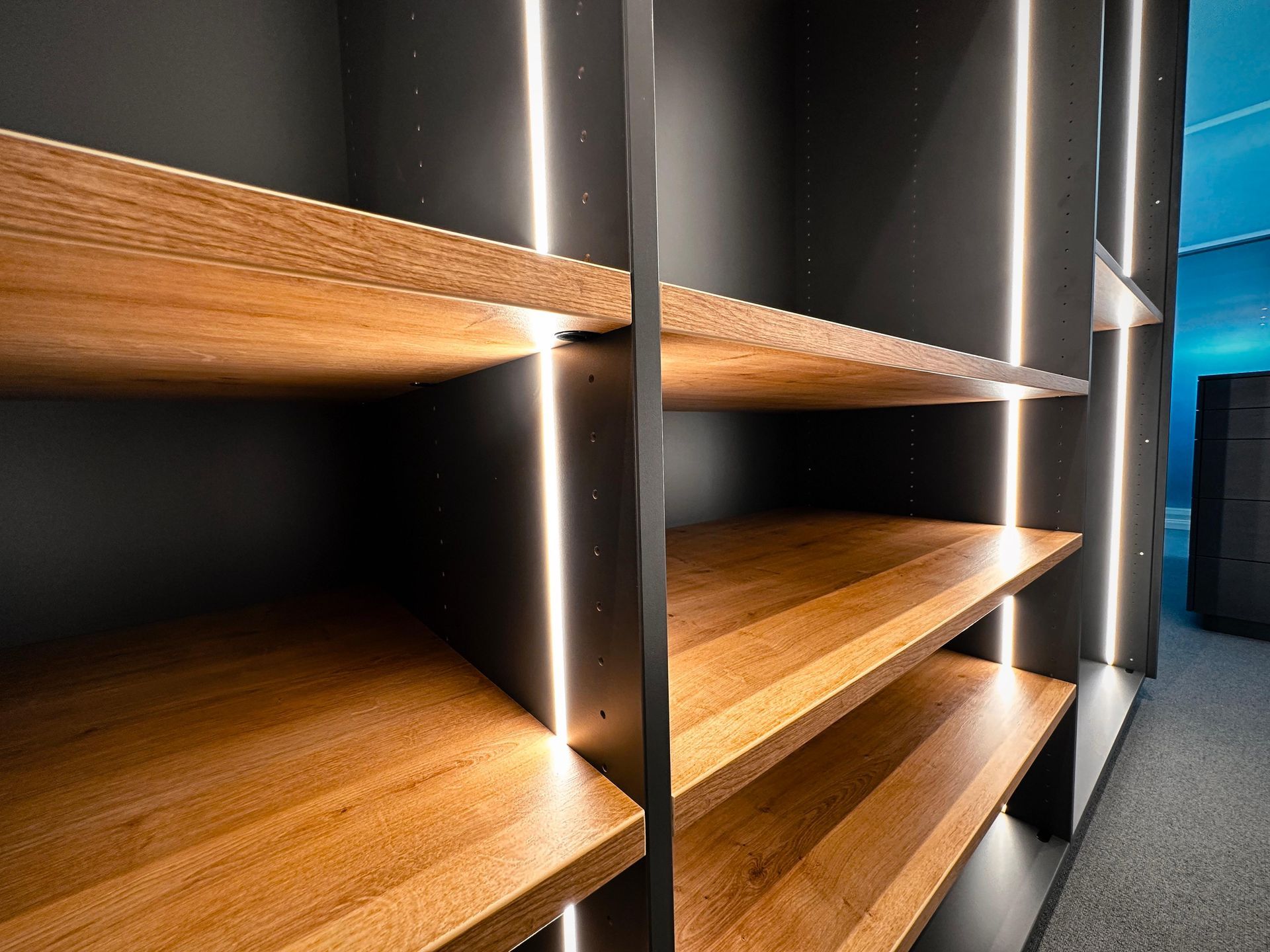 Moderne Holzregale mit integrierter LED-Beleuchtung in einem dunklen Flur