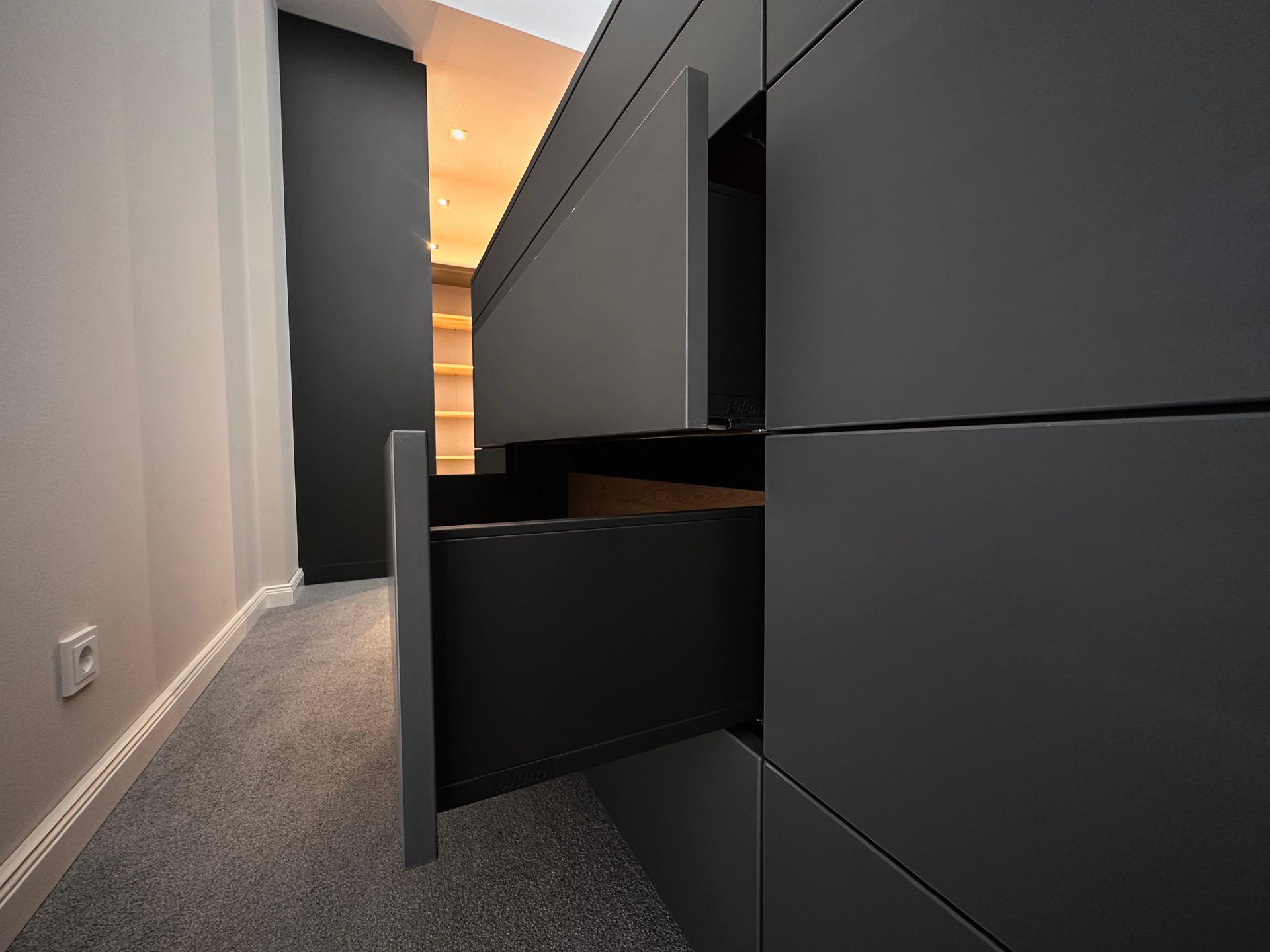 Flur mit dunkelgrauen Einbauschränken und einer offenen Schublade in einem modernen Interieur