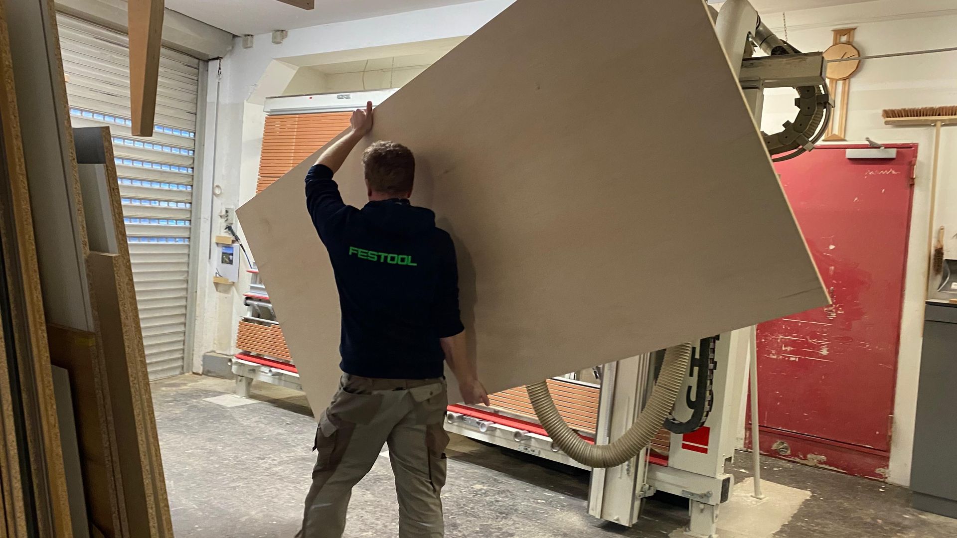Arbeiter trägt eine große beige Platte durch einen schmalen Flur.