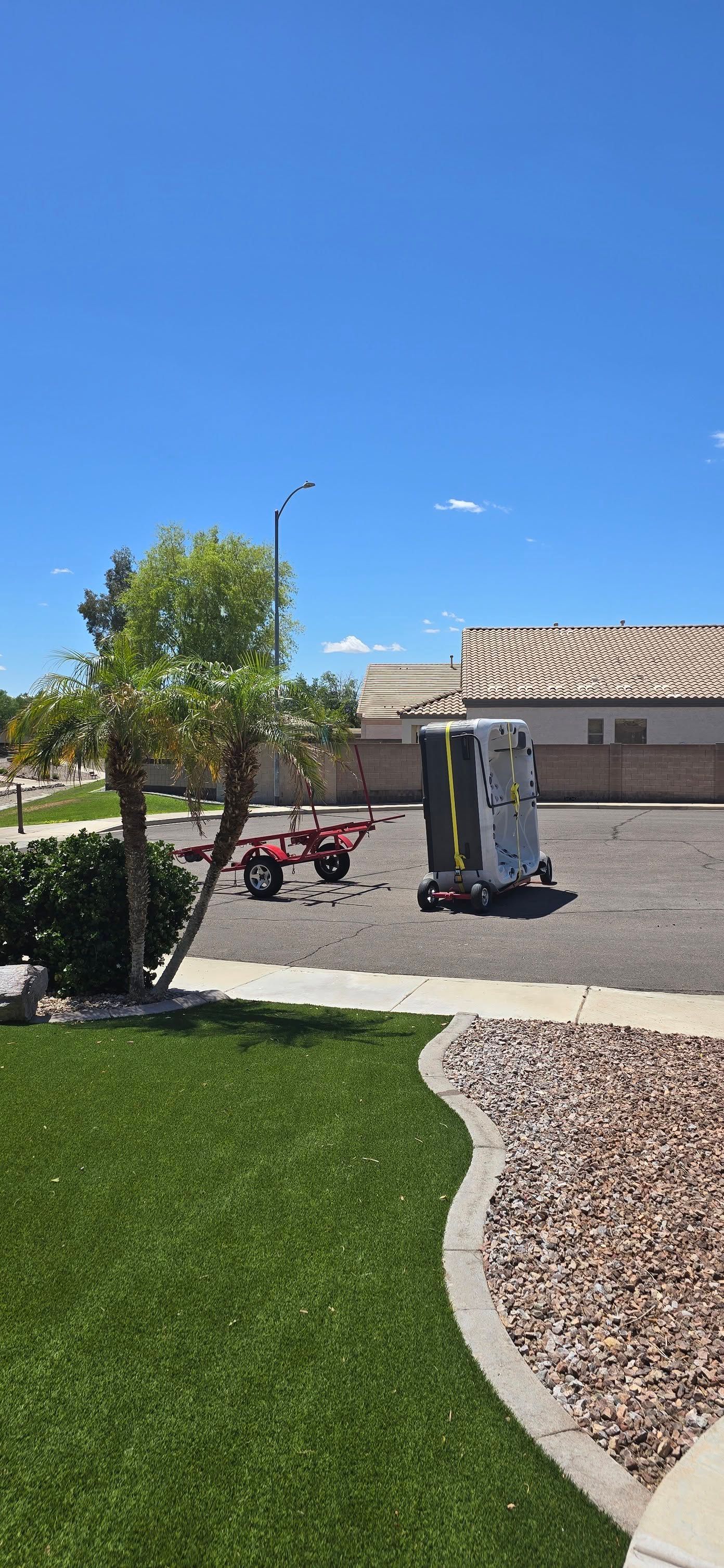 Suburban driveway with a red stroller, exercise machine, tree, and blue sky
