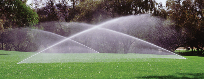 Two sprinklers spraying water on a lush green field