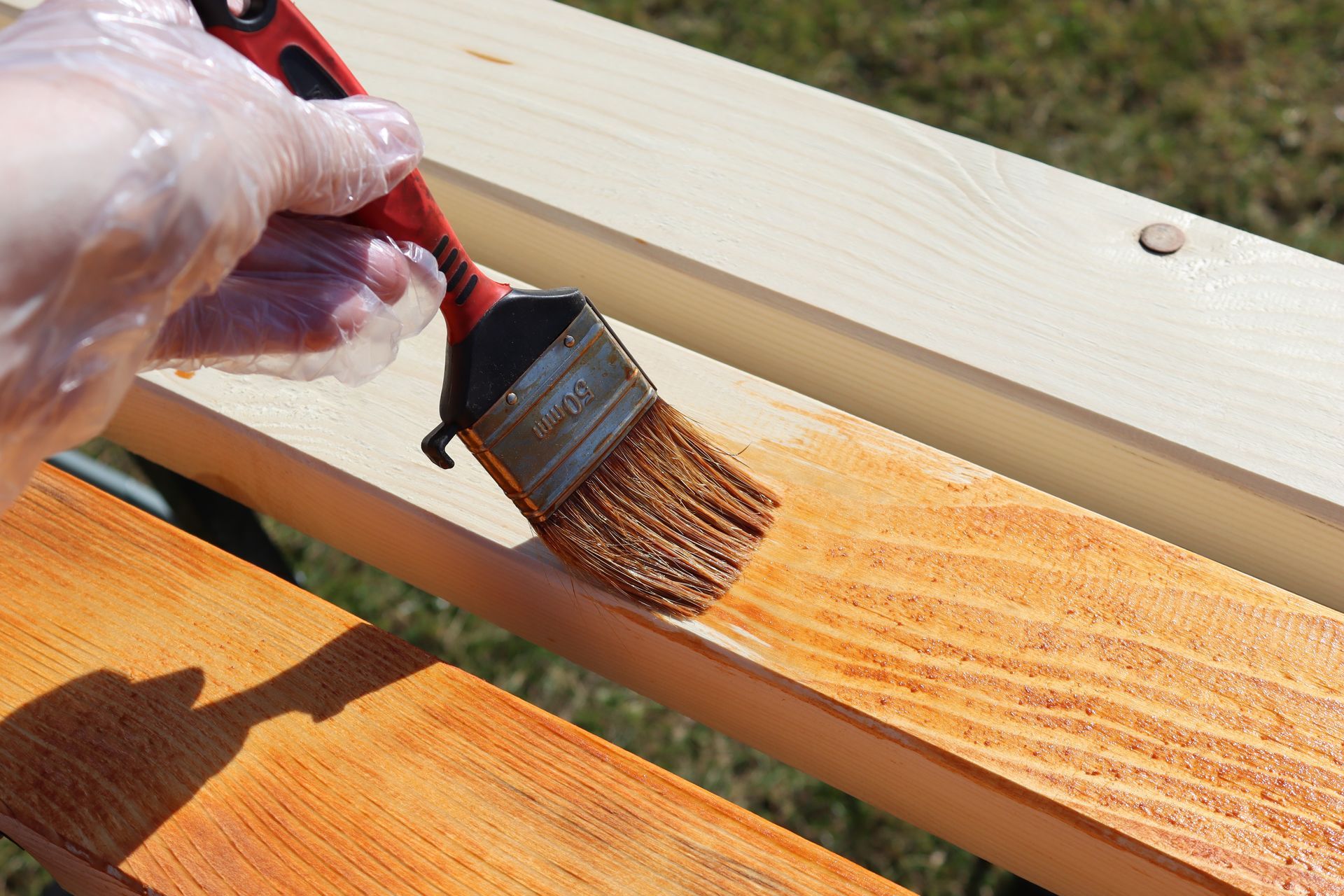 A person is painting a piece of wood with a brush.