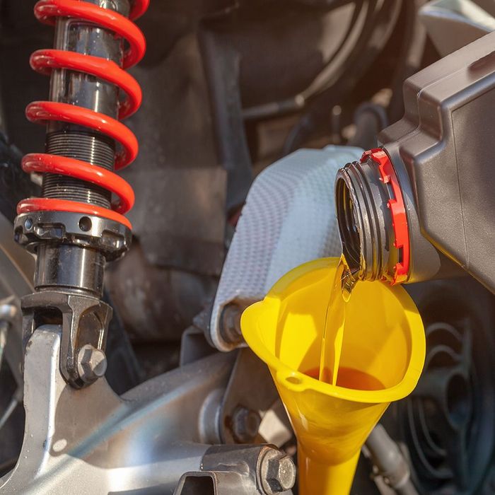 a bottle of oil is being poured into a yellow funnel .