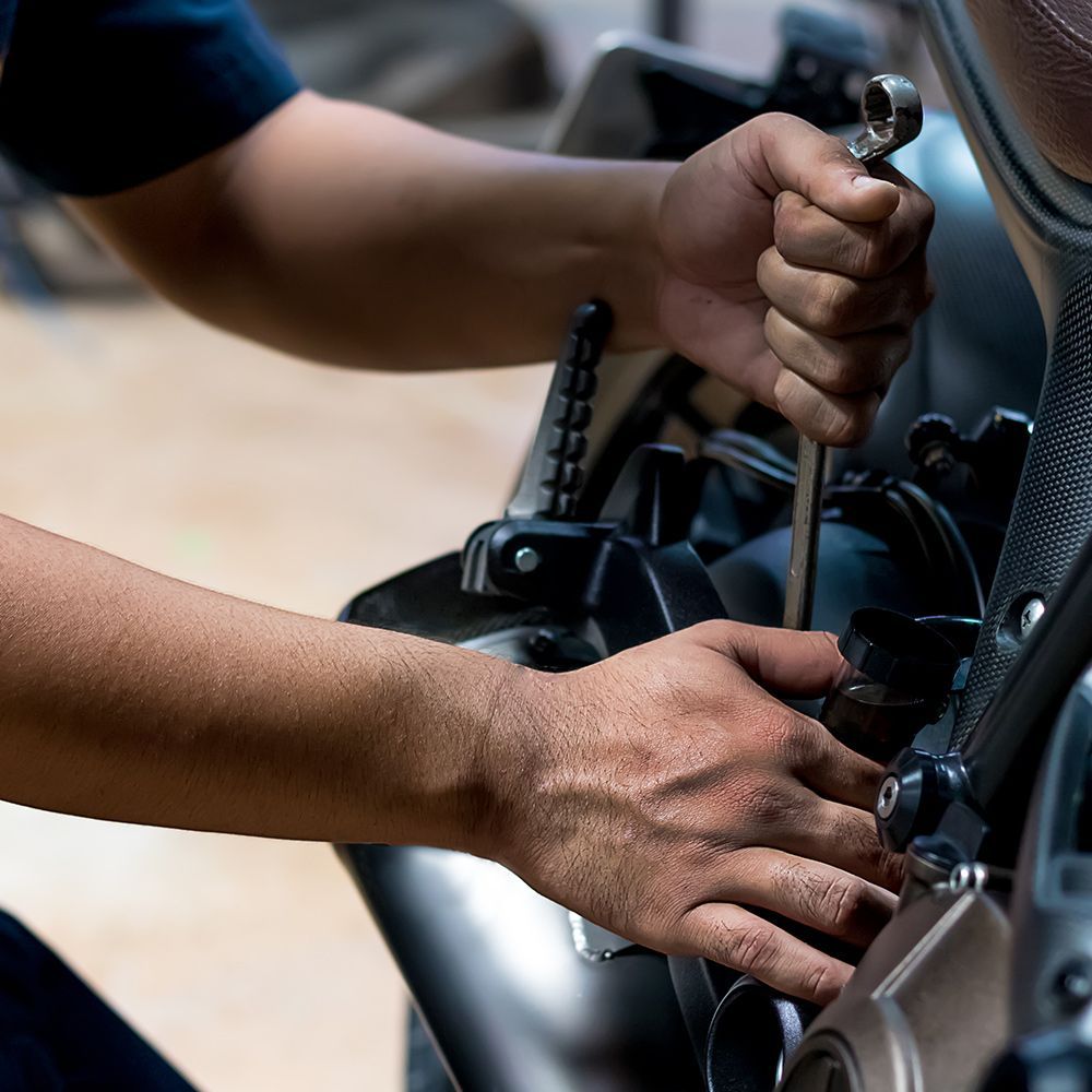 a man is working on a motorcycle with a wrench .