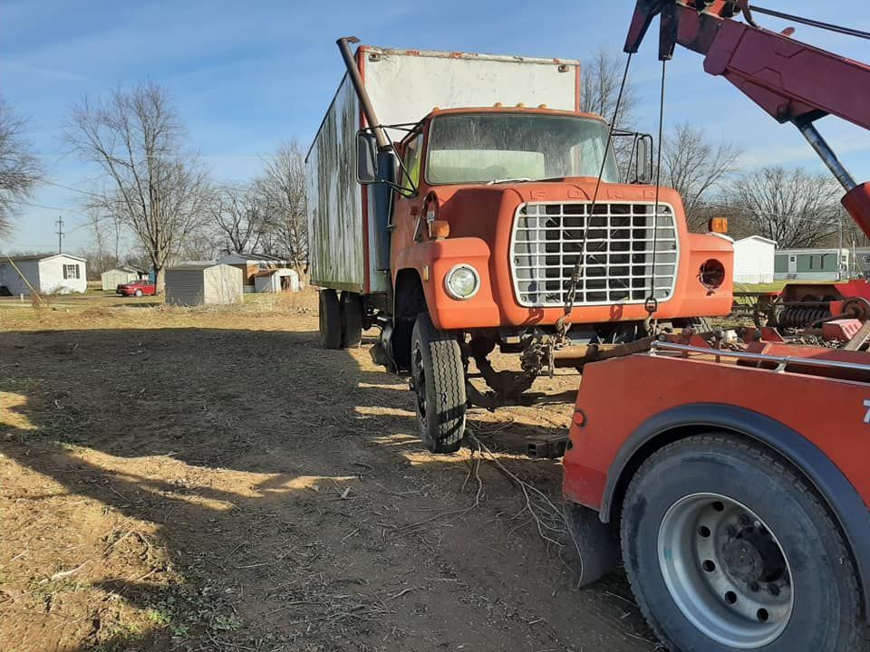 A ford truck is being towed by a tow truck