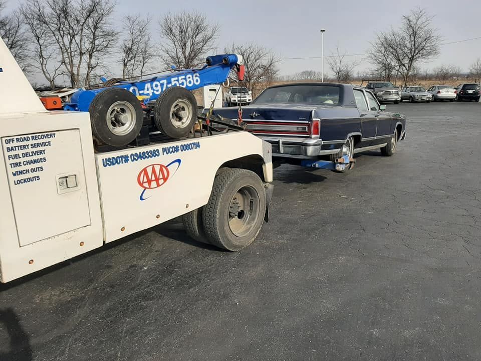 A tow truck is towing a car in a parking lot