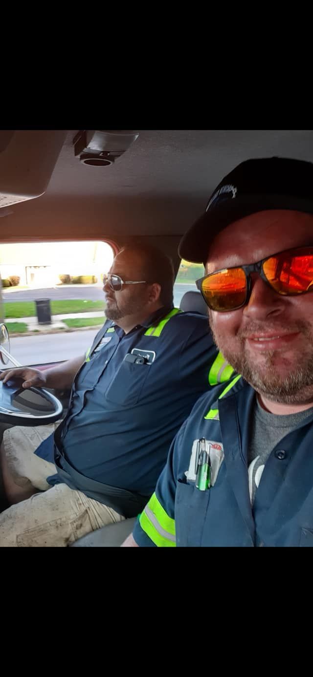 Two men are sitting in a car wearing sunglasses.