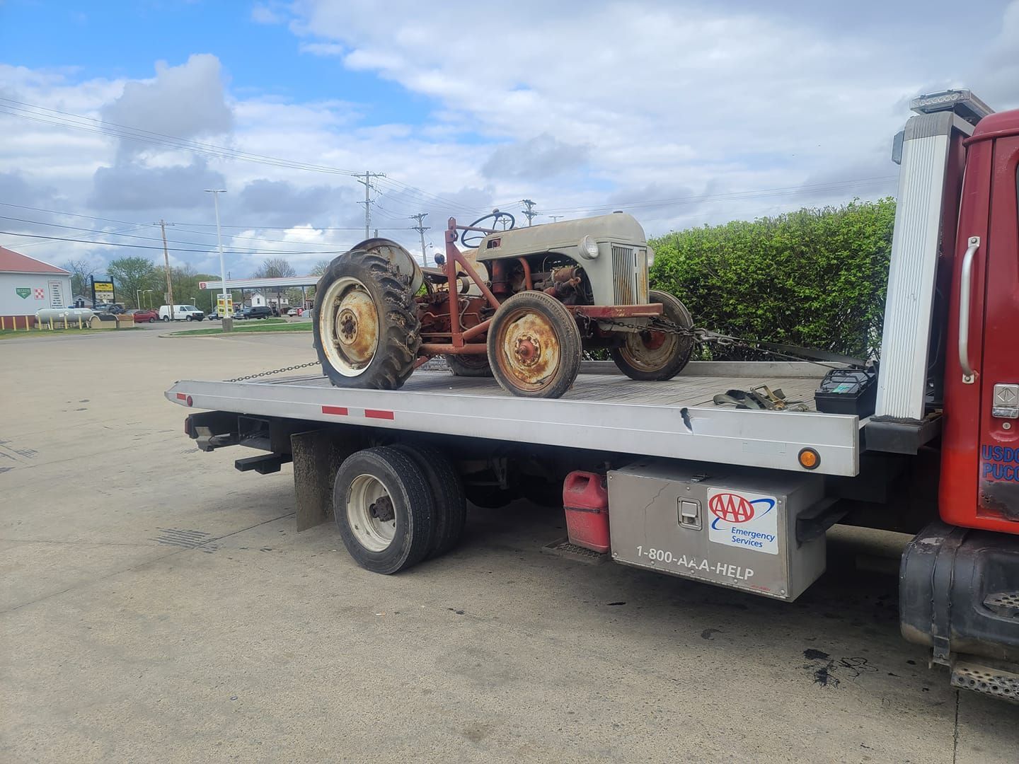 An old tractor is being towed by a tow truck.