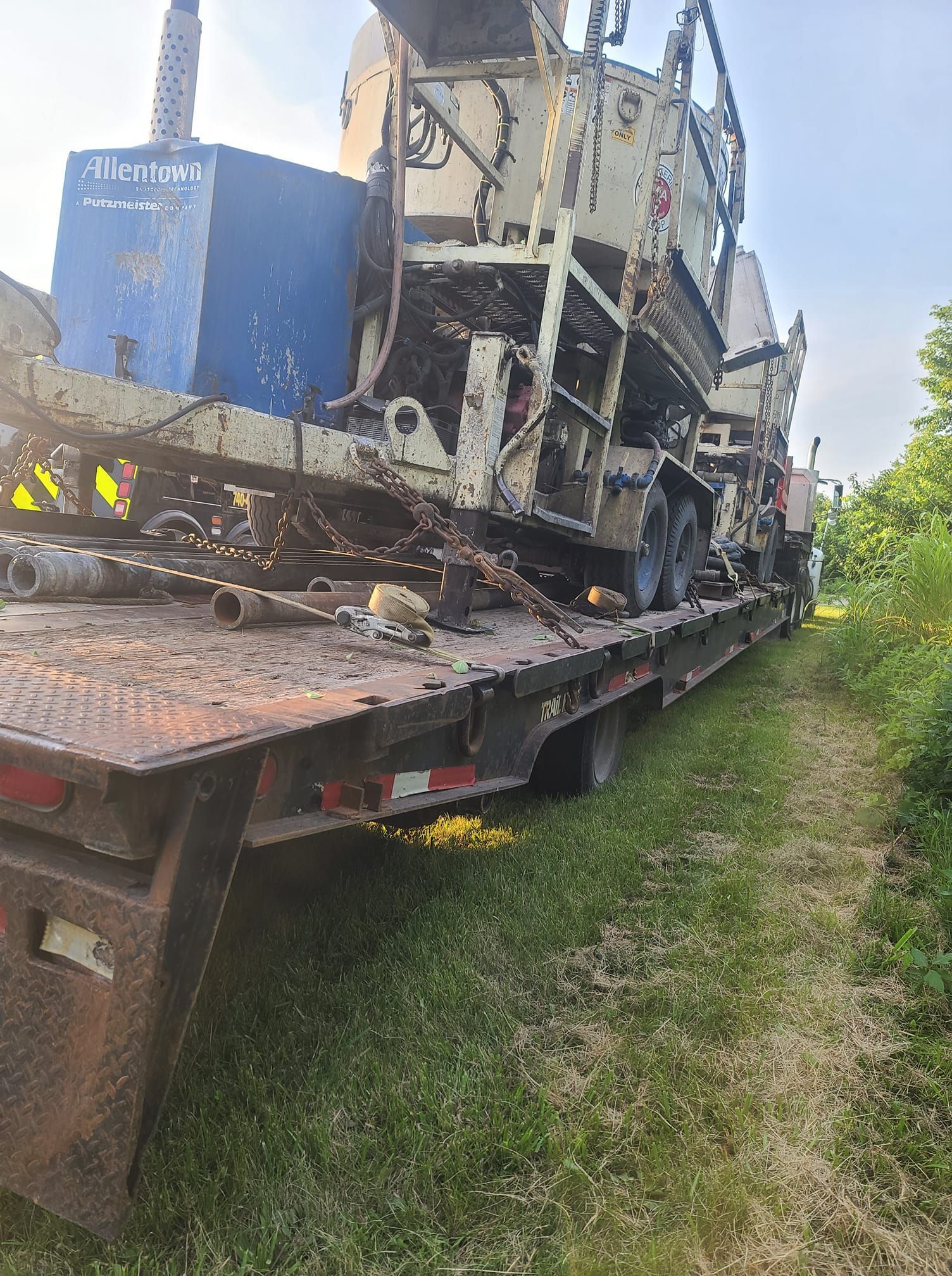 A tow truck is carrying a large machine on a flatbed trailer.