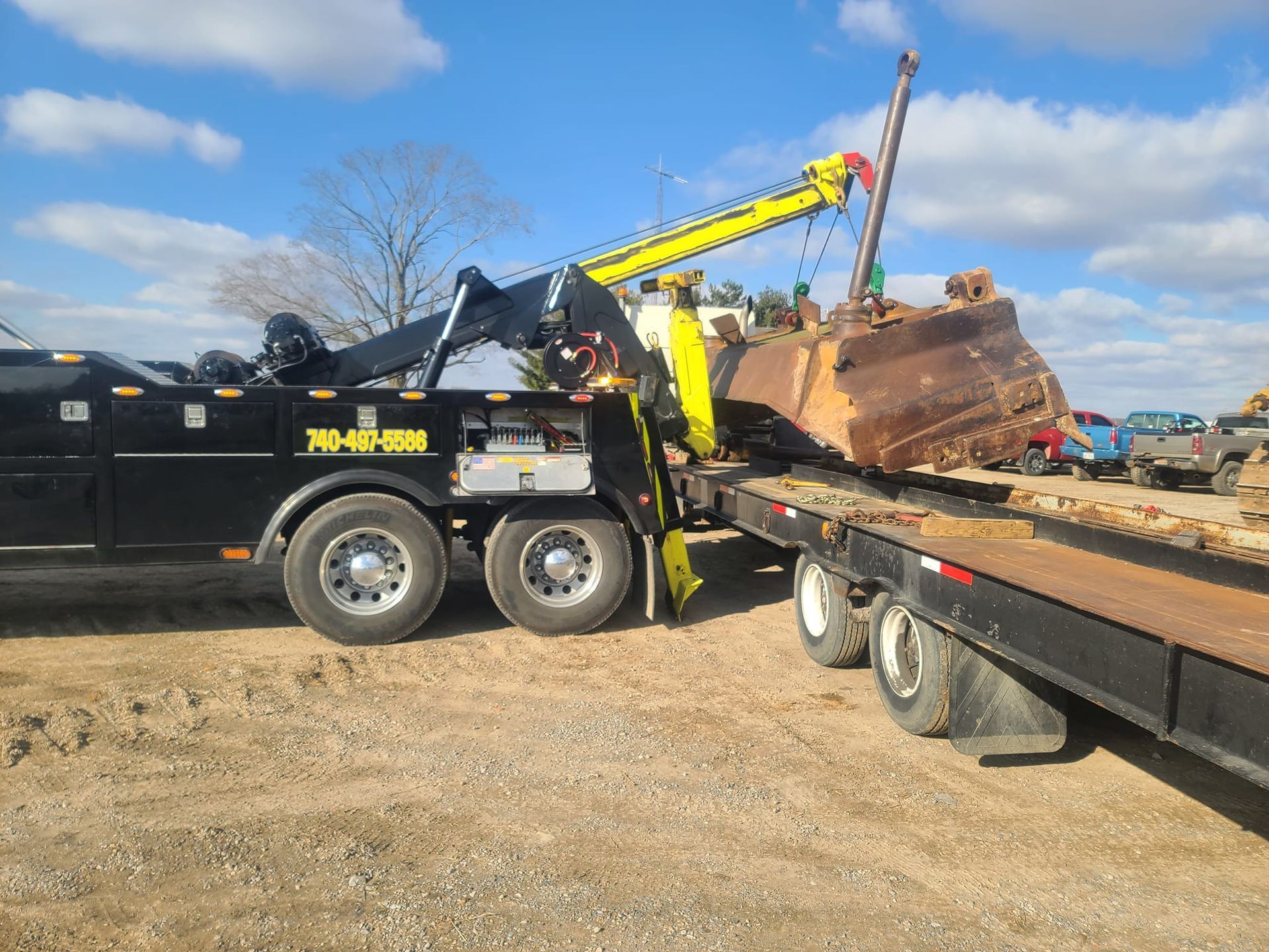 A tow truck is carrying a bulldozer on a flatbed trailer.