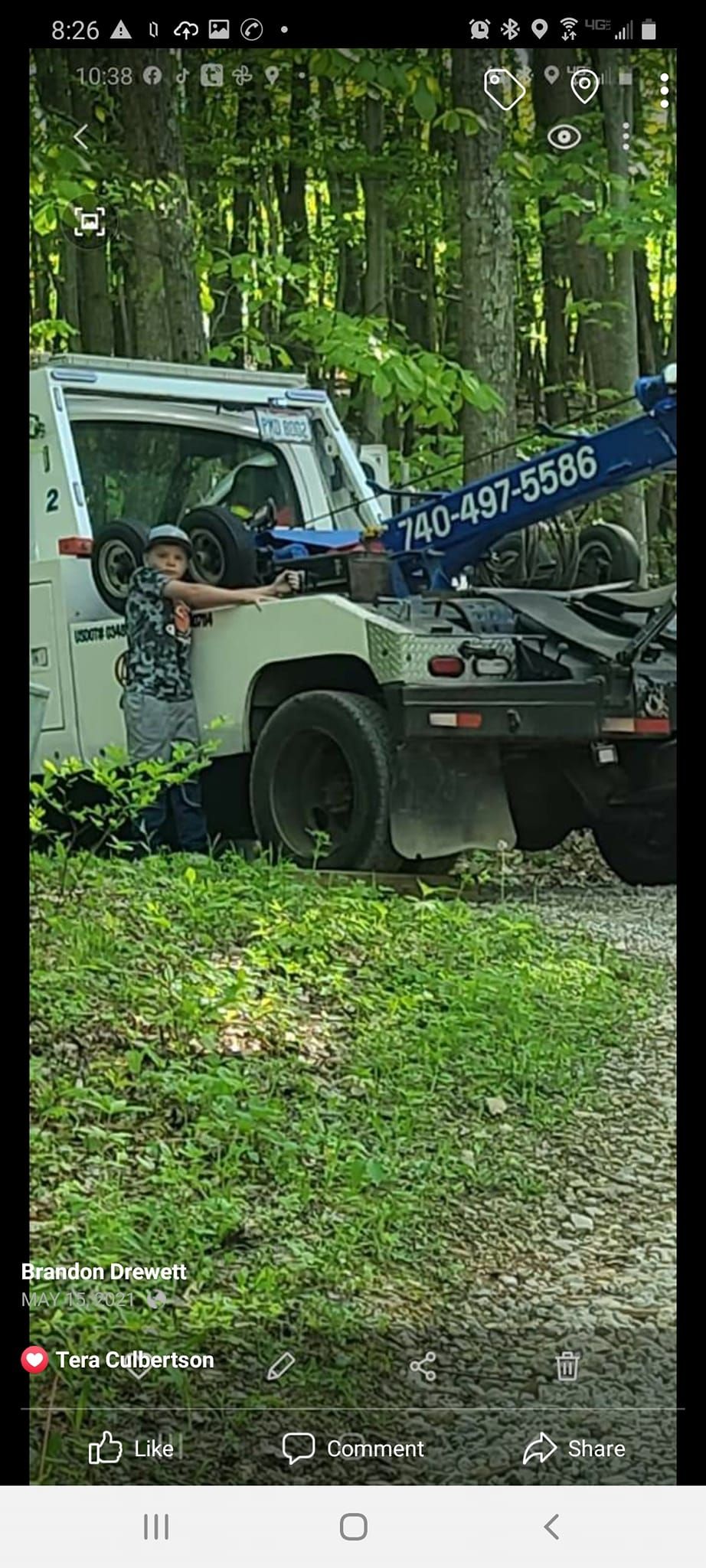 A tow truck is sitting on the side of the road in the woods.