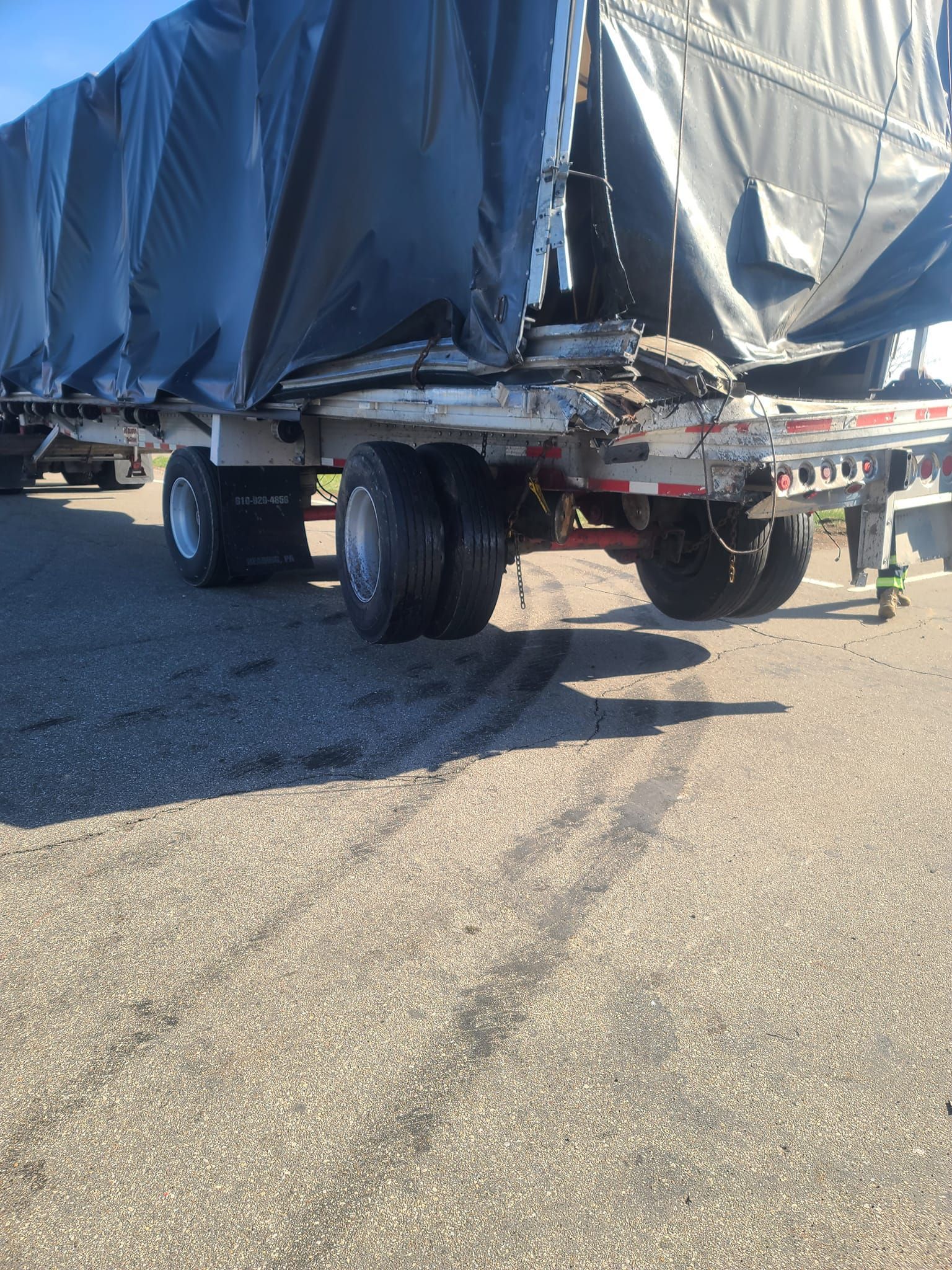 A semi truck with a tarp on it is parked on the side of the road.