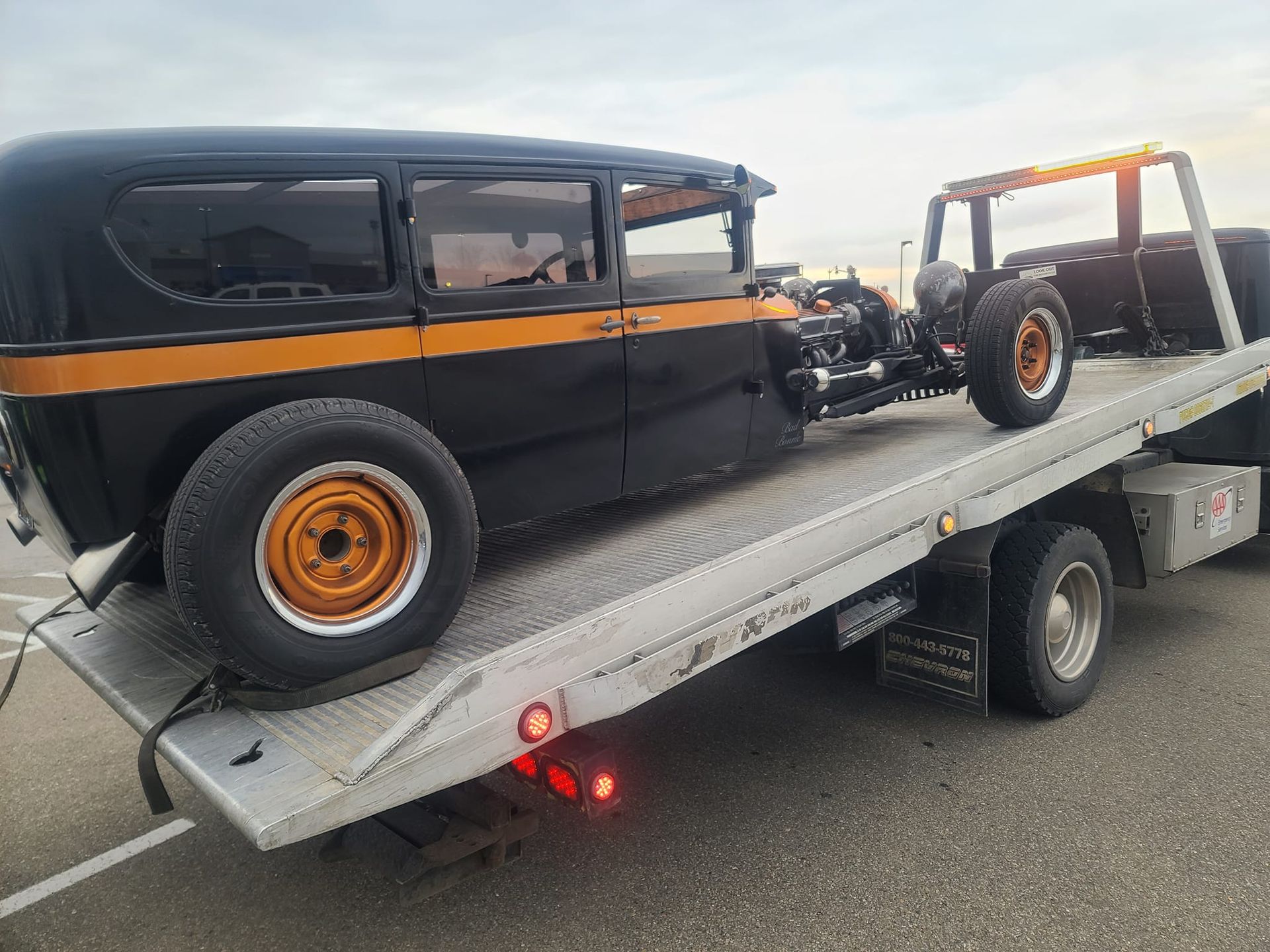 An old car is being towed by a tow truck.