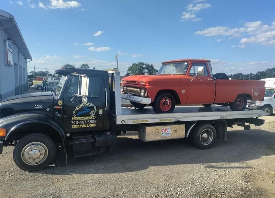 A black tow truck with a red truck on the back of it