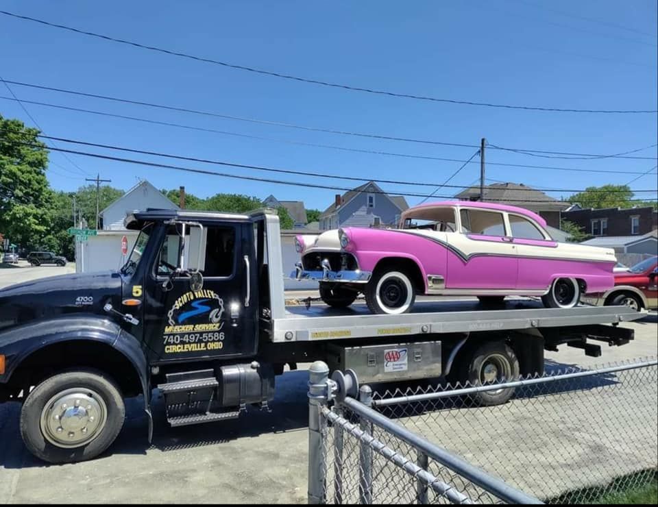 A pink car is being towed by a tow truck