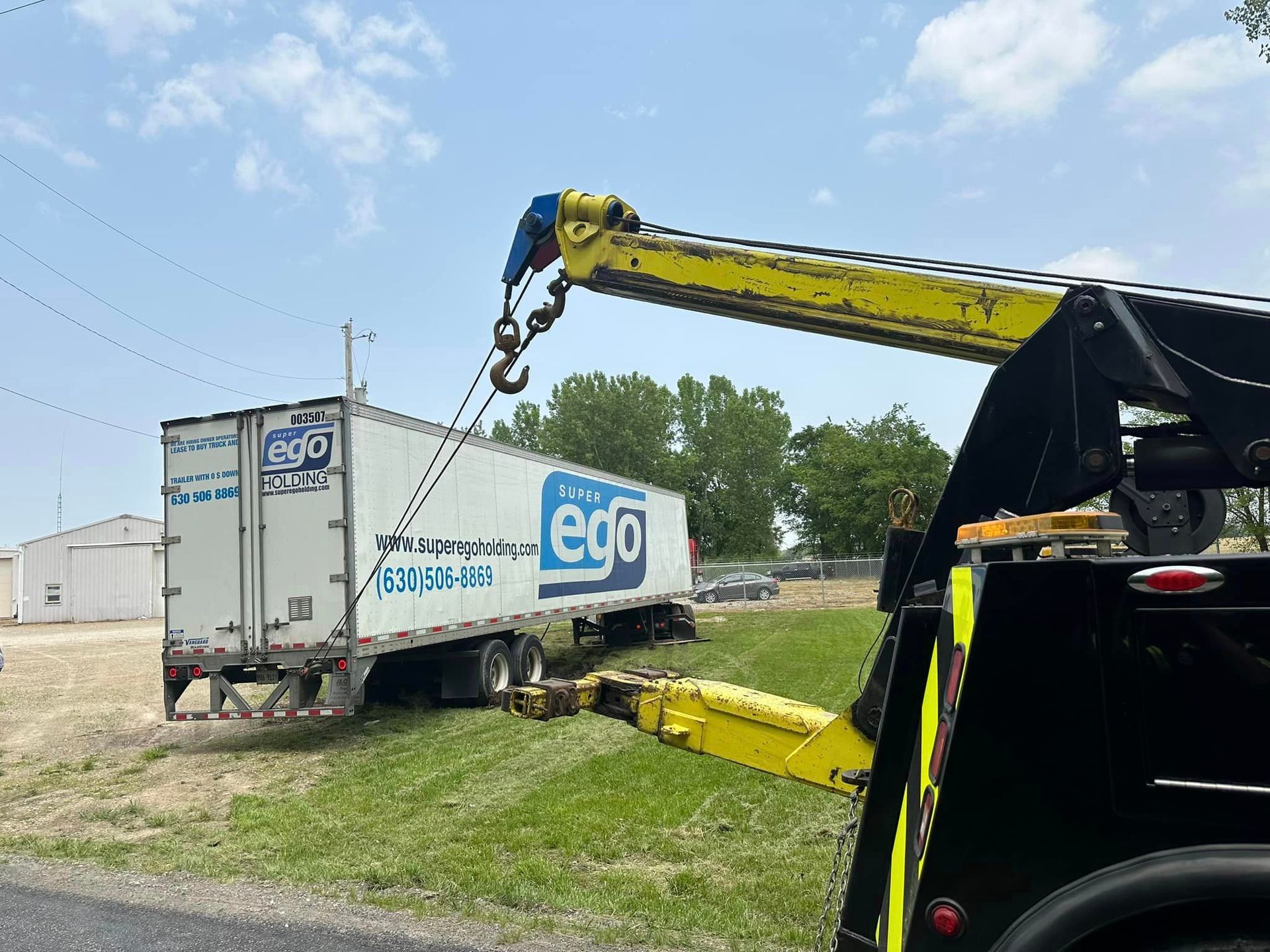 A white semi truck is being towed by a tow truck.