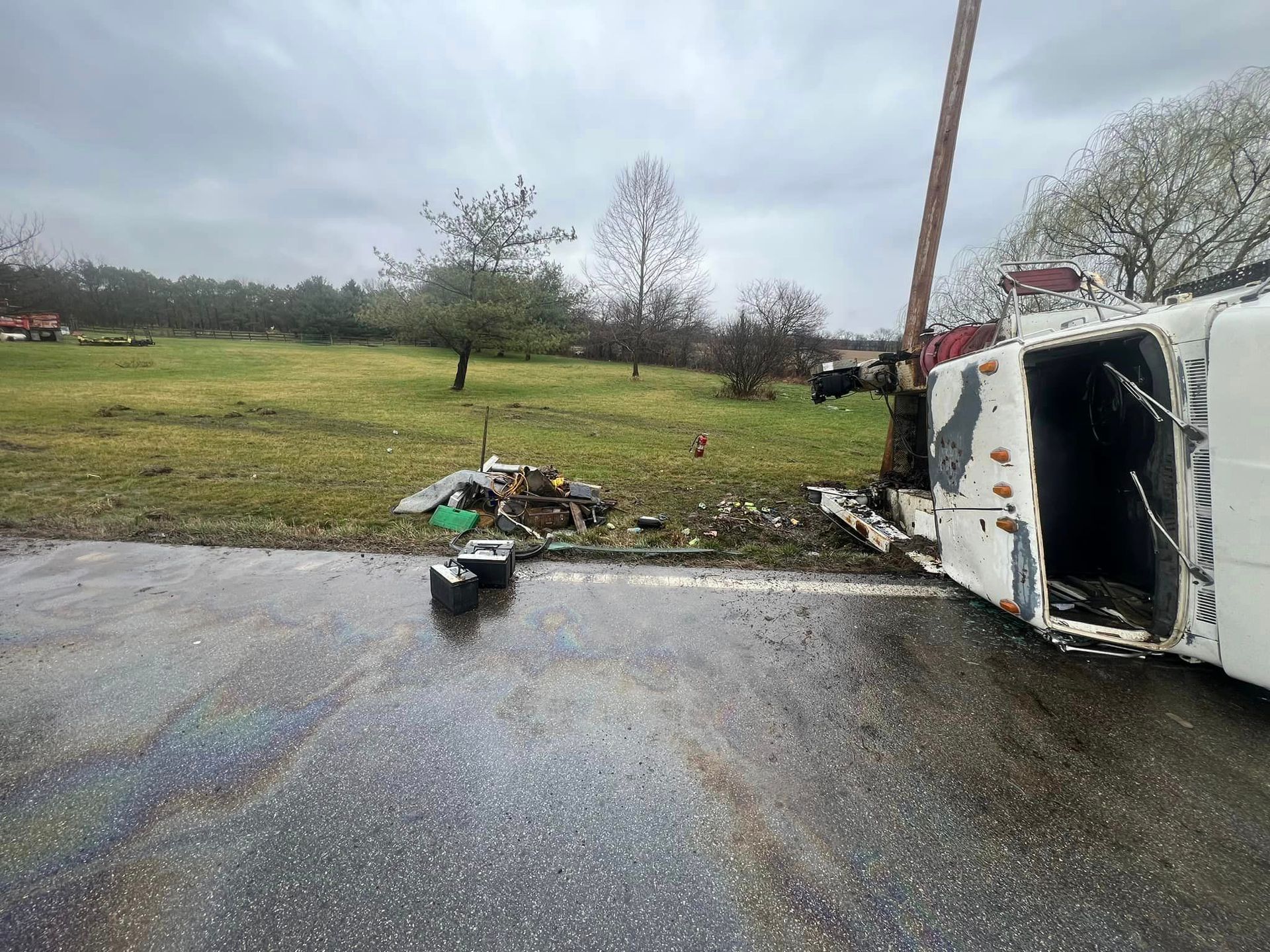 A white truck is turned over on the side of the road.