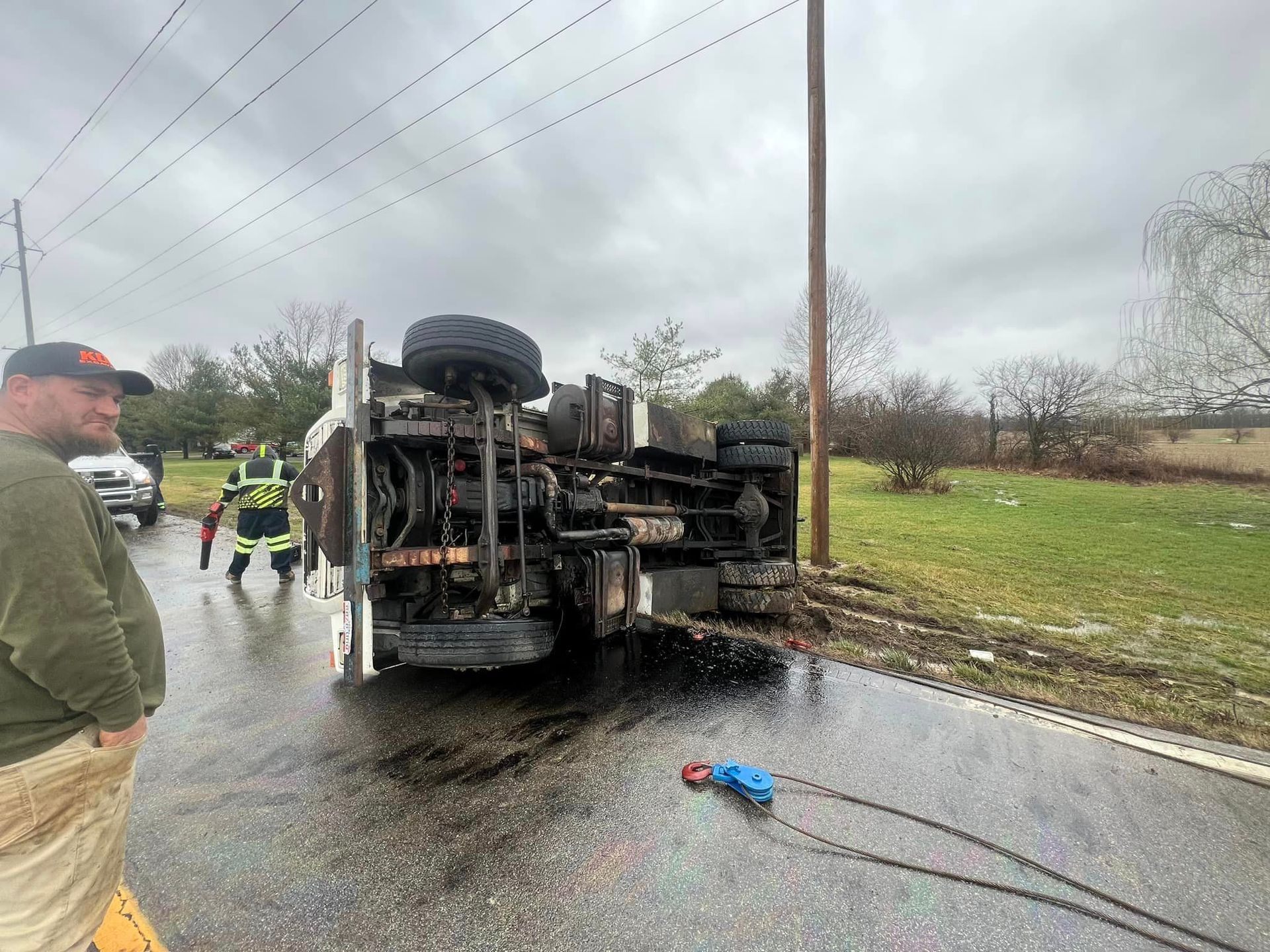A truck is on its side on the side of the road.