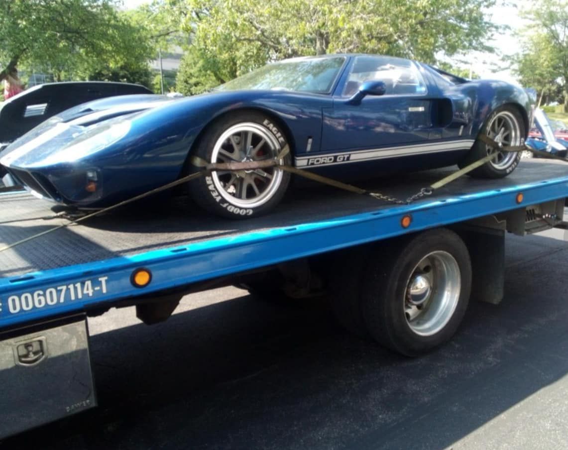 A blue sports car is being towed by a tow truck