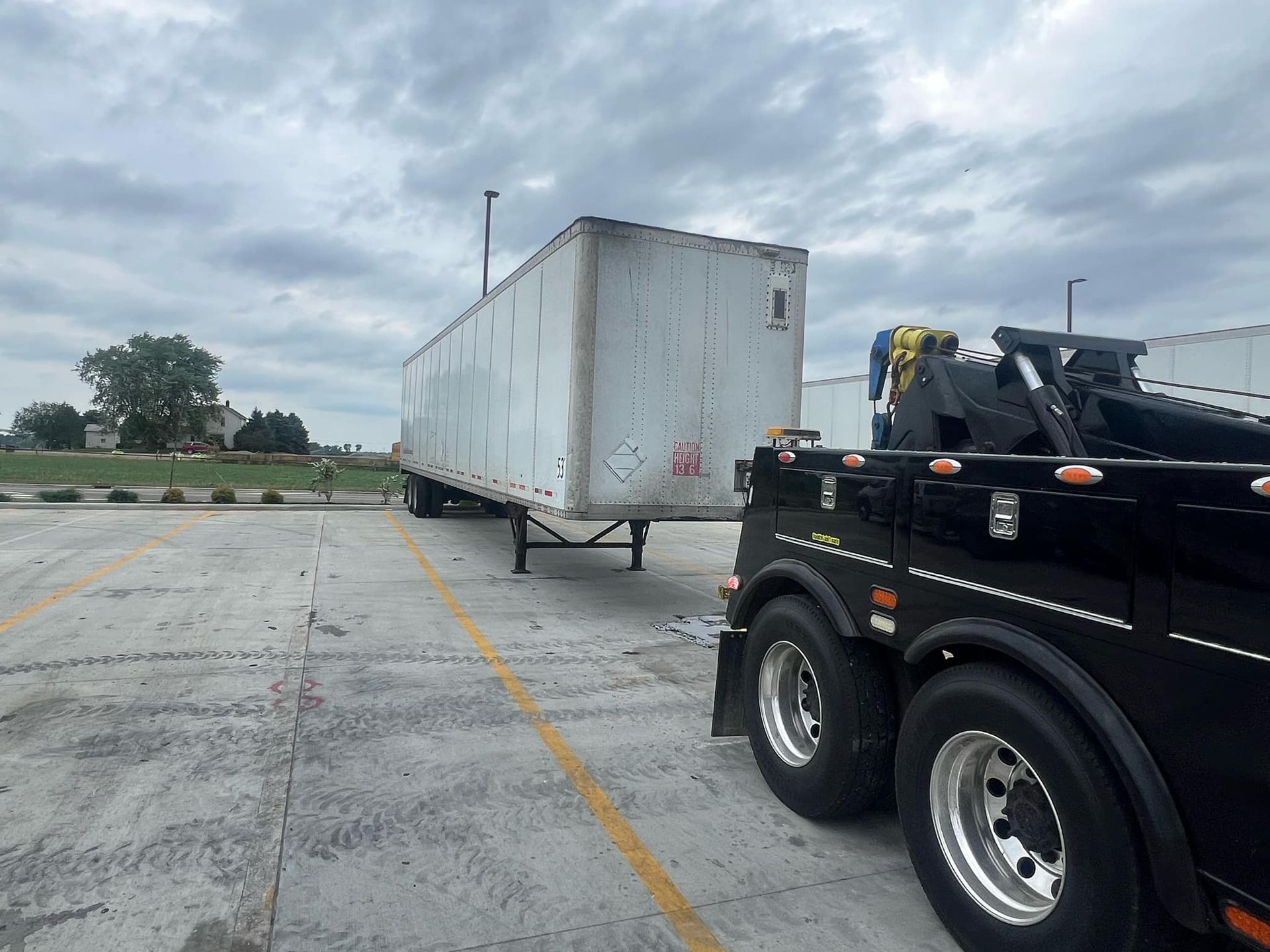 A semi truck is being towed by a tow truck in a parking lot.