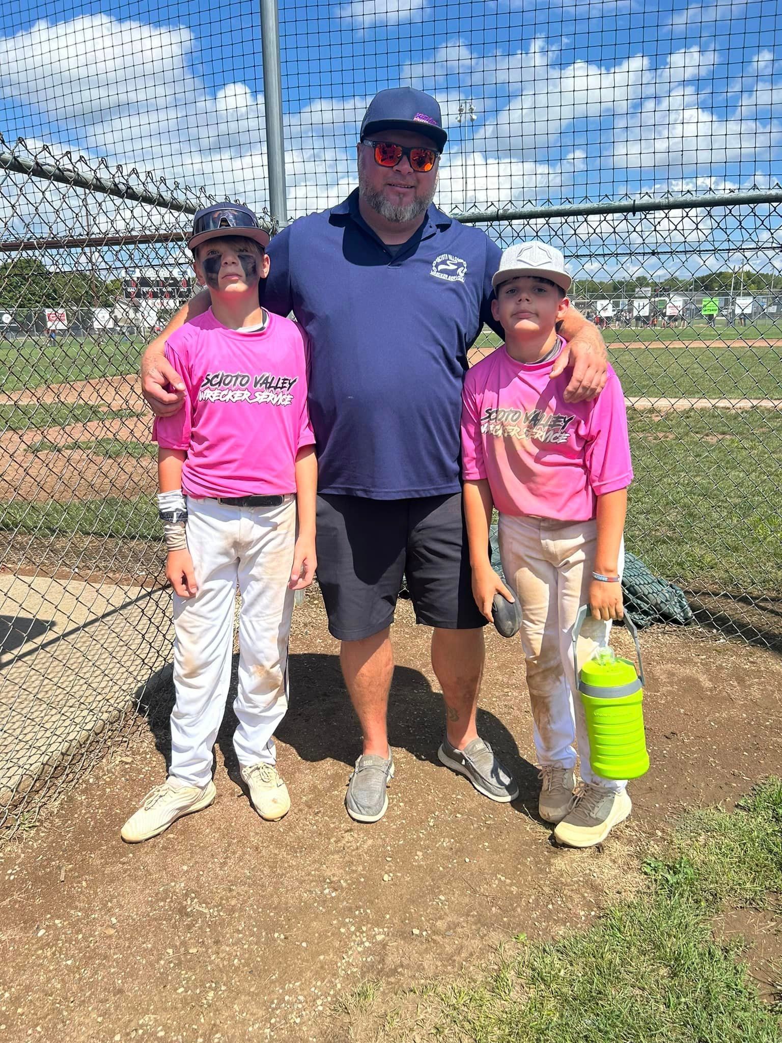 A man and two children are posing for a picture on a baseball field.
