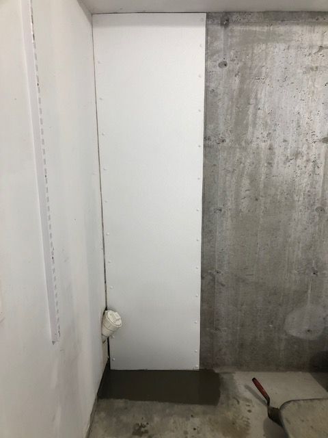Narrow corner with white wall, concrete wall, floor gap, and a red-handled tool on the floor