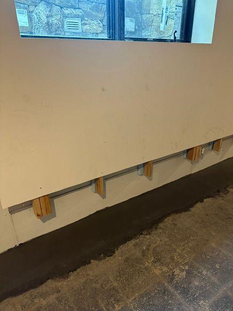 Partially finished wall with exposed studs beneath a window in a room with a concrete floor.