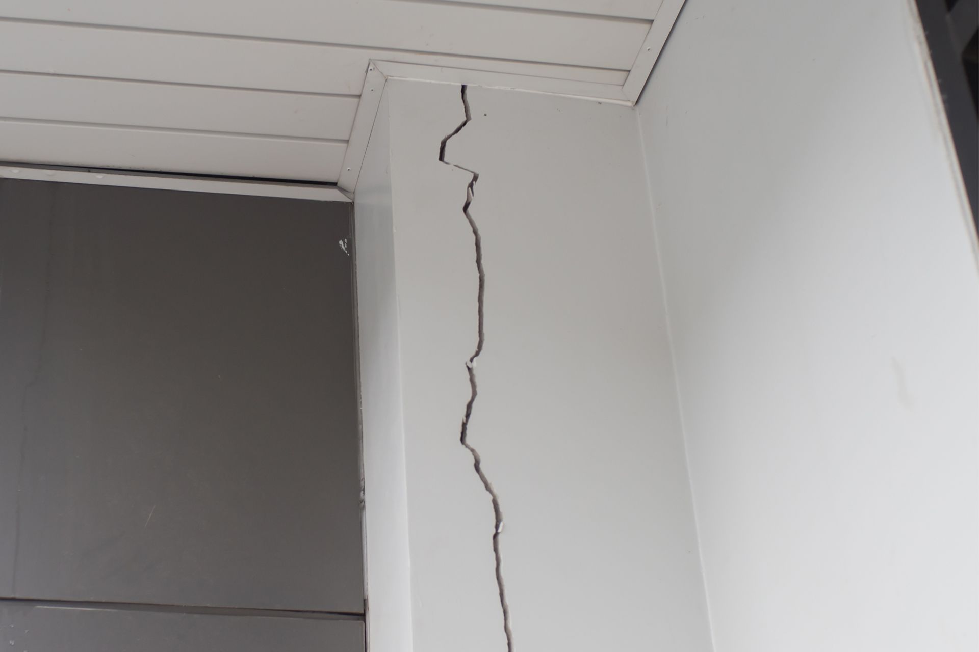 Tall interior wall with a long vertical crack near the ceiling