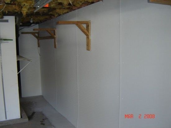 Concrete basement floor with a long drain along the wall and exposed utility panels.