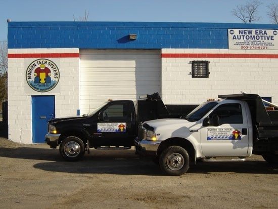 Two pickup trucks parked outside a blue and white automotive garage