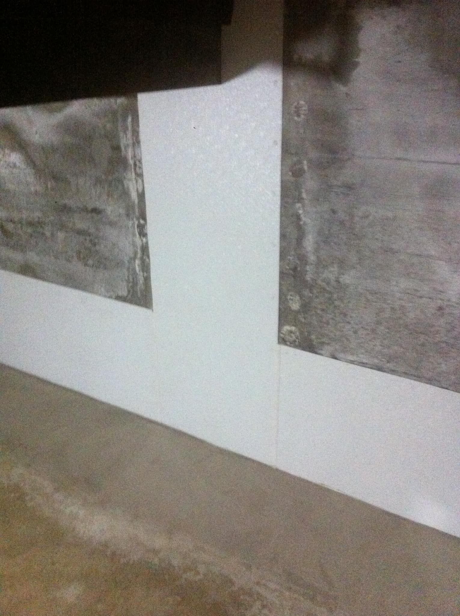 Two gray panels on a wall above a white section and beige floor trim.