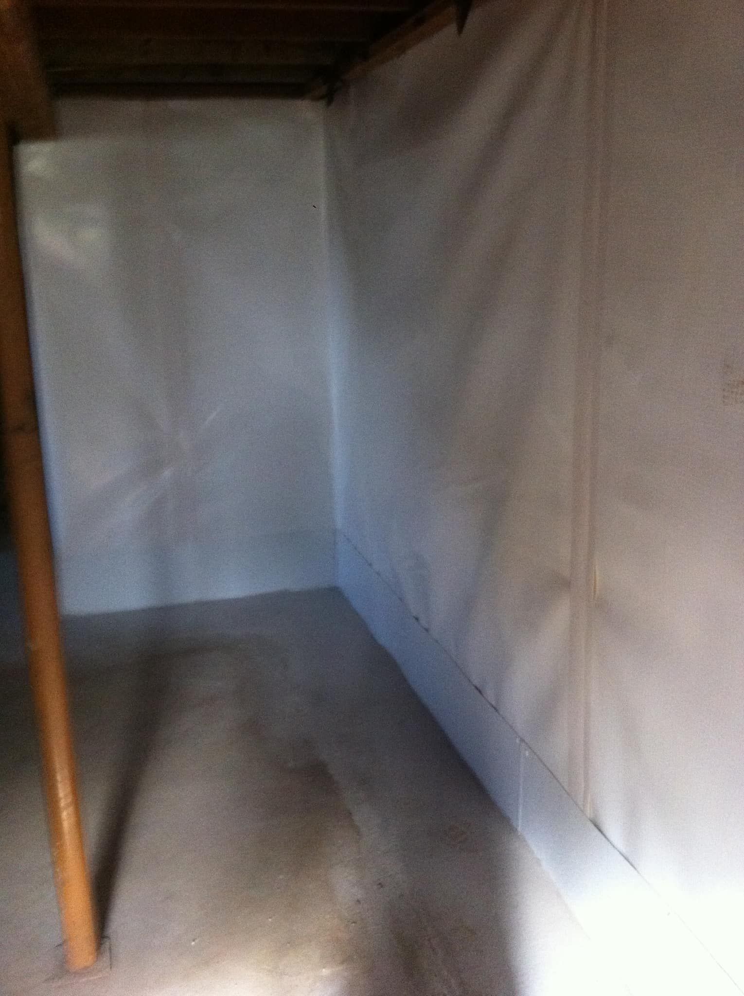 Empty fabric-covered storage nook with a gray floor and wooden post on the left.