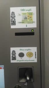 A vending machine with two stickers on it and a coin slot.