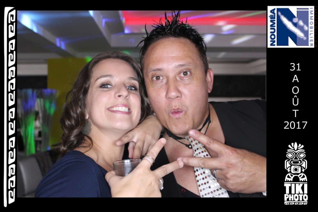 A man and a woman pose for a photo in a tiki photo booth