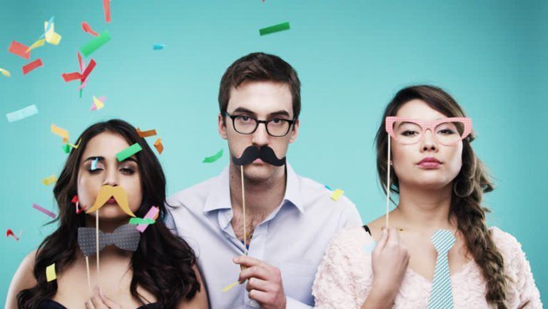 A man and two women are holding fake mustaches in front of their faces.