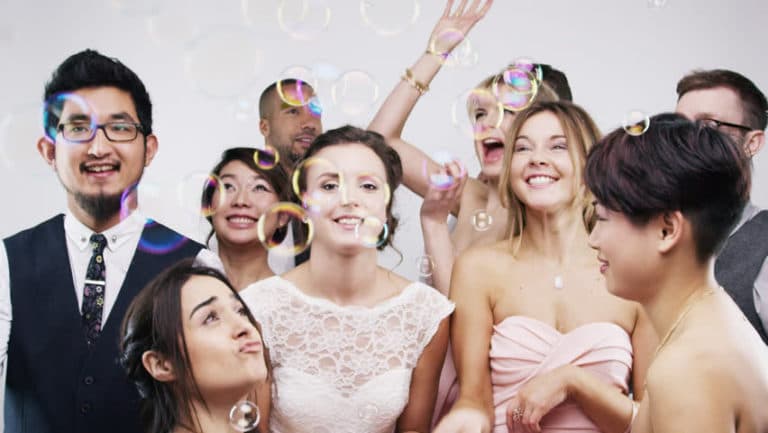 A group of people are blowing soap bubbles at a wedding reception.